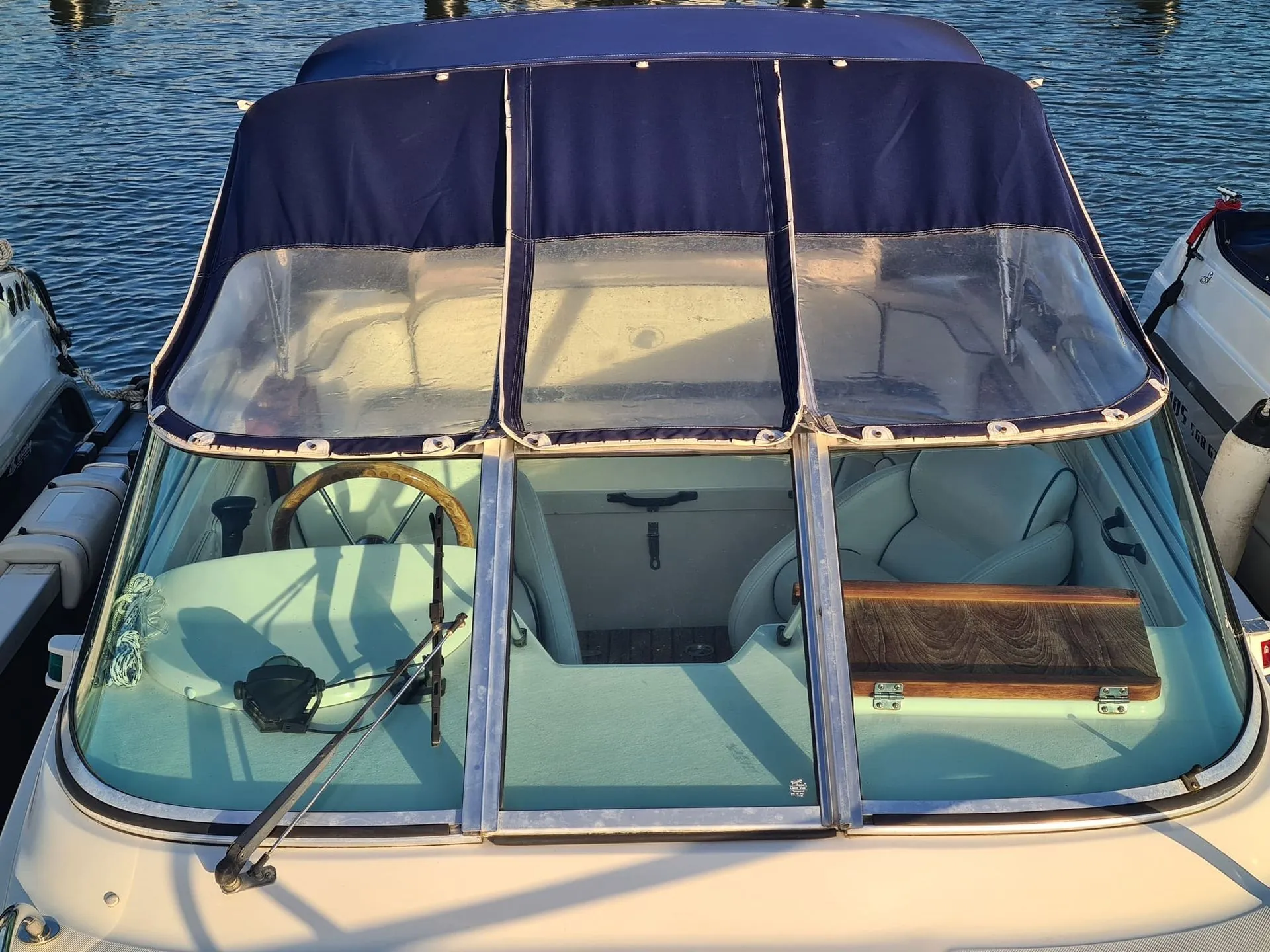 Boat cabin with open canvas top and windshield showing interior seating and helm station dockside.