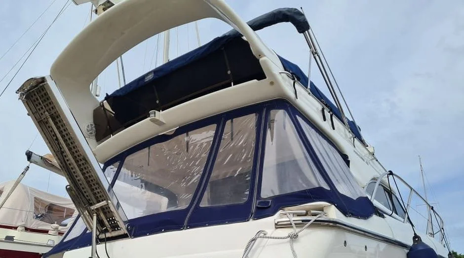 Fiberglass cabin cruiser with navy canvas canopy and weathered hull detail.