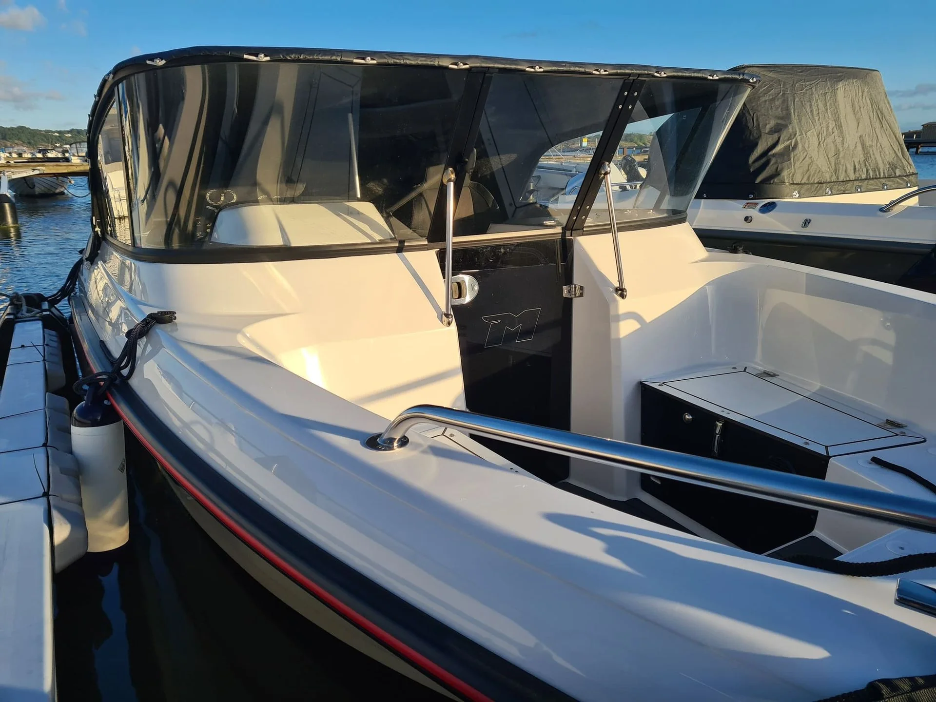 Fiberglass cabin cruiser moored at Jacksonville marina with open cabin door and canvas canopy.