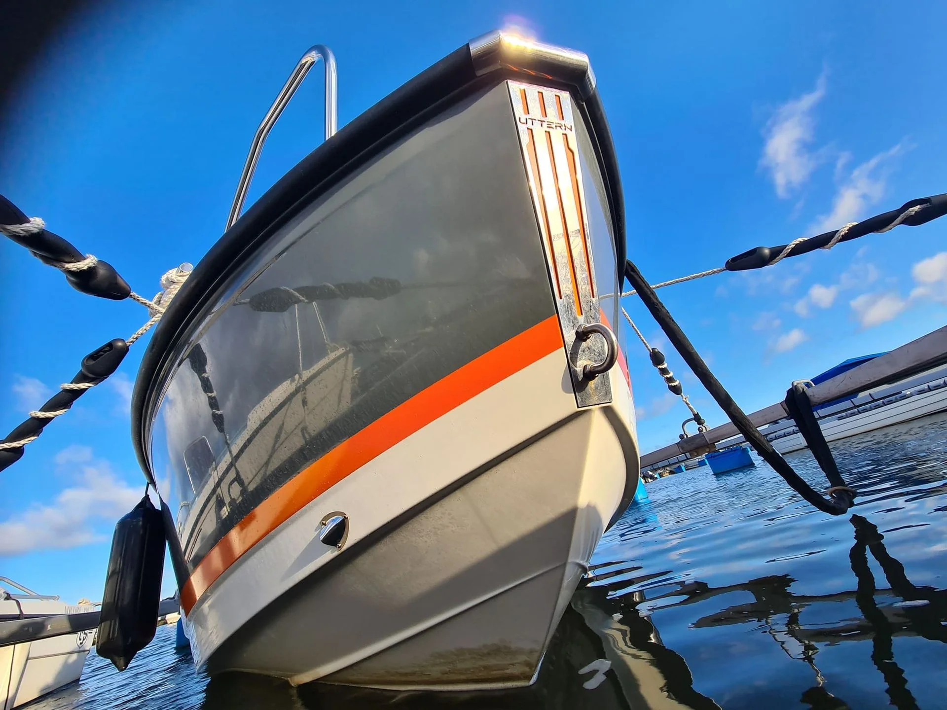 Fiberglass motorboat with orange stripe moored at Jacksonville dock under clear sky.