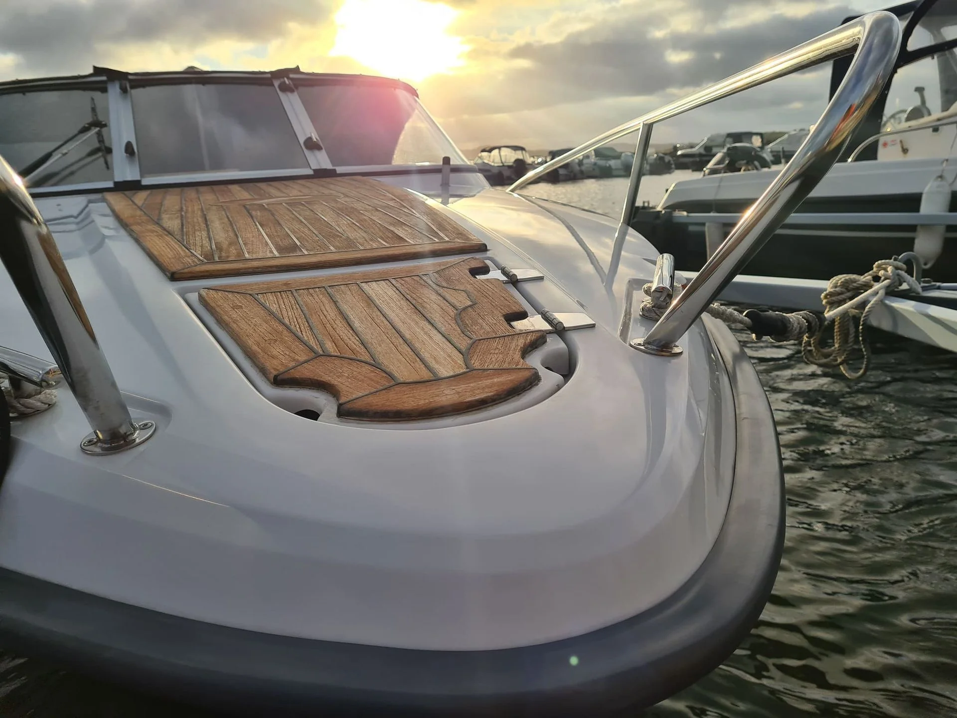 Fiberglass boat hull with wooden deck detail moored at Jacksonville marina during golden hour.