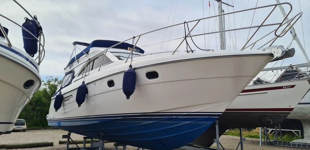 Fiberglass motorboat on dry-dock trailer showing hull and rigging in Jacksonville marine yard.