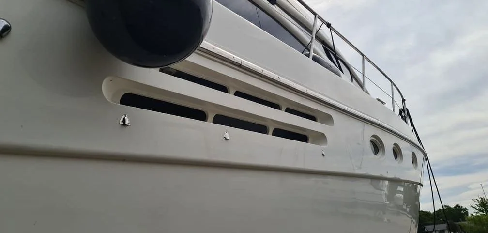 Large white fiberglass boat hull showing ventilation ports and weathered surface detail.