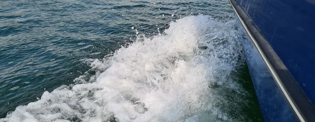 Boat hull cutting through ocean waves during high-speed run in Jacksonville waters.