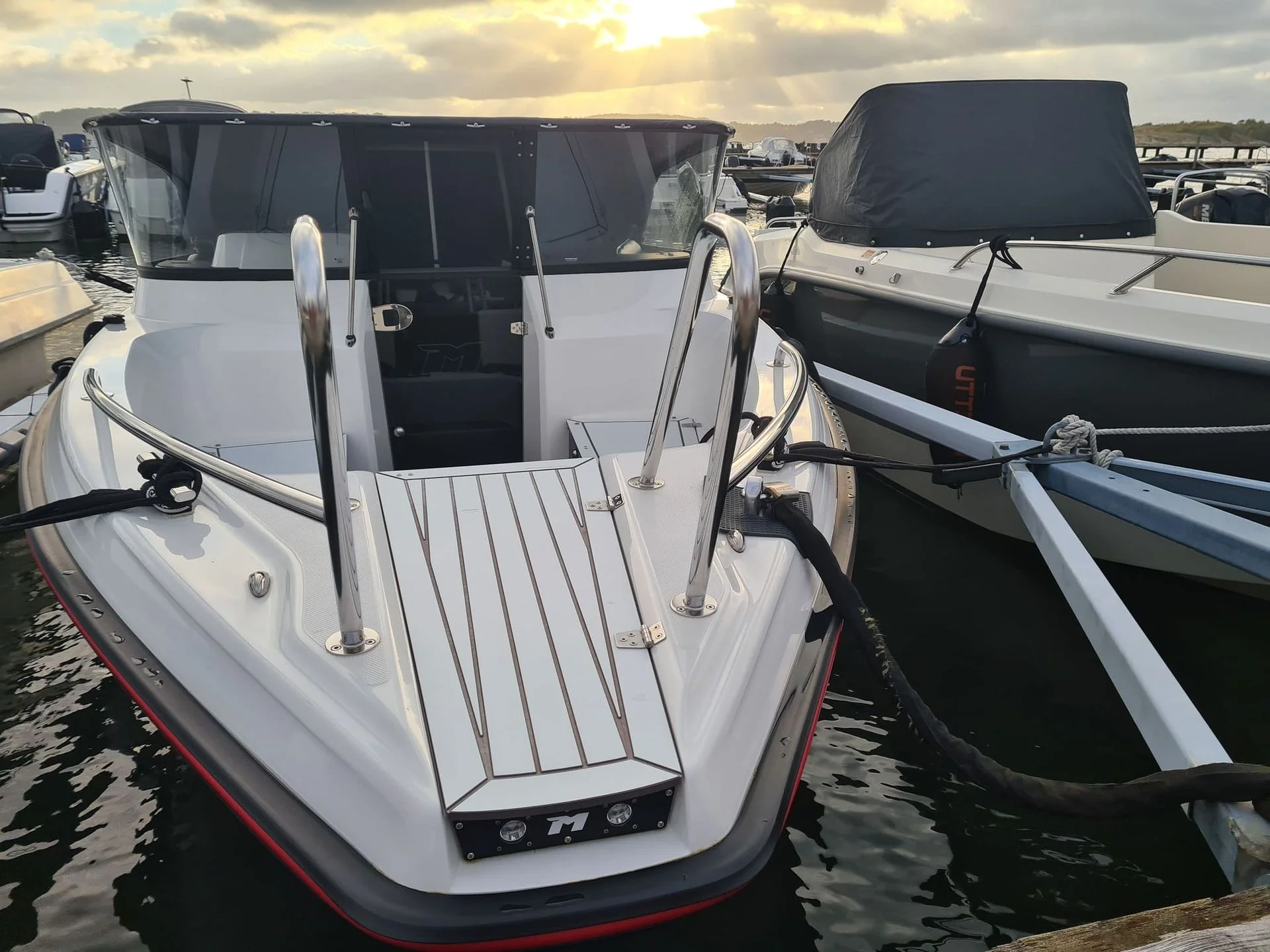White fiberglass motorboat moored at Jacksonville marina among other vessels, showing clean hull and cabin.