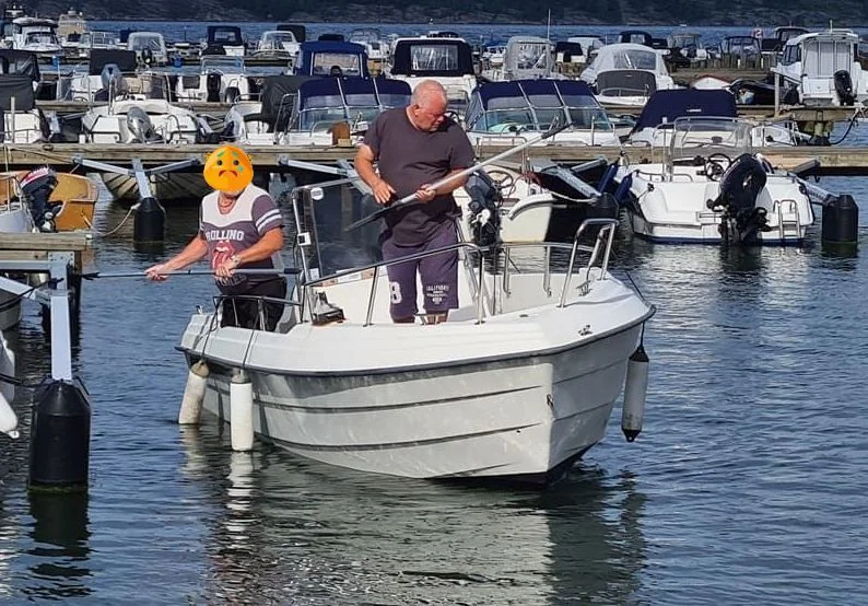 Two people on white fiberglass boat at Jacksonville marina during daytime service inspection.