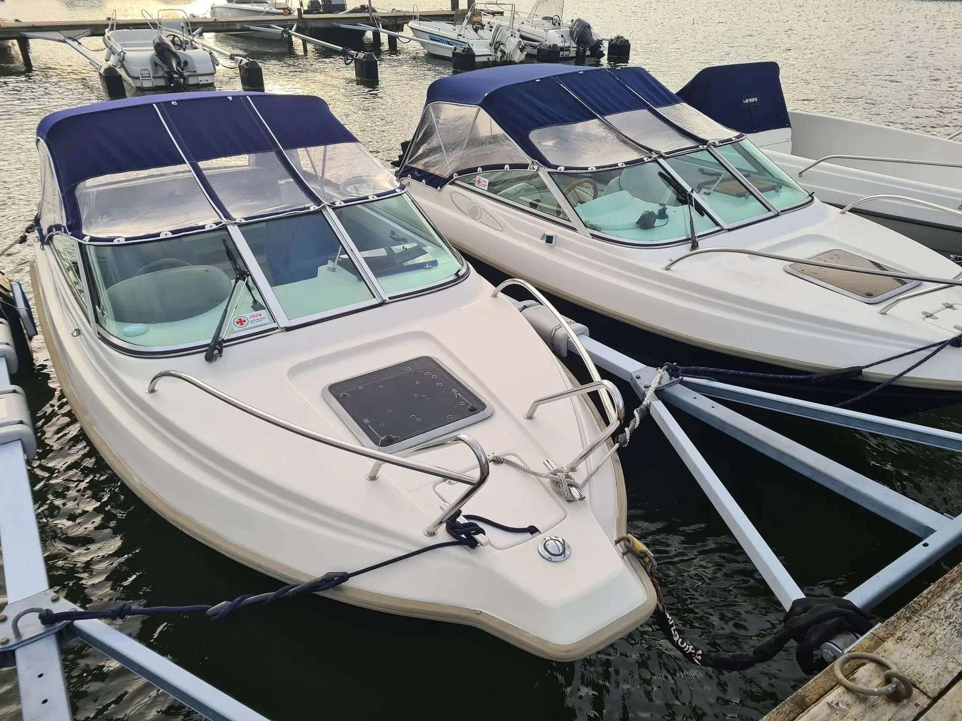 Multiple fiberglass motorboats moored at Jacksonville marina showing varied hull conditions and canvas covers.