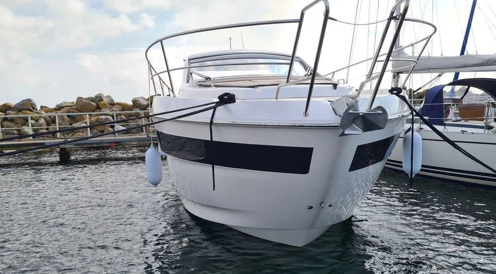 White fiberglass motorboat moored at Jacksonville marina with visible hull weathering and rigging.