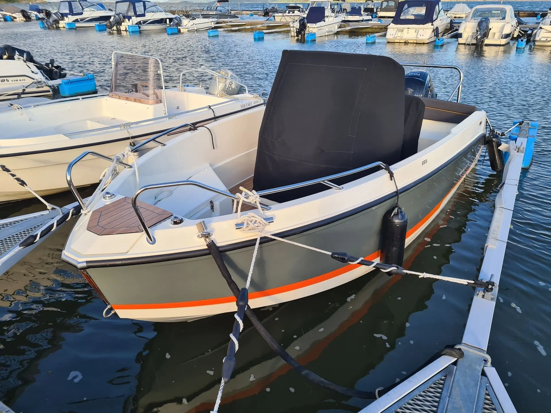 Fiberglass motorboat with black engine cover moored at Jacksonville marina dock among other vessels.