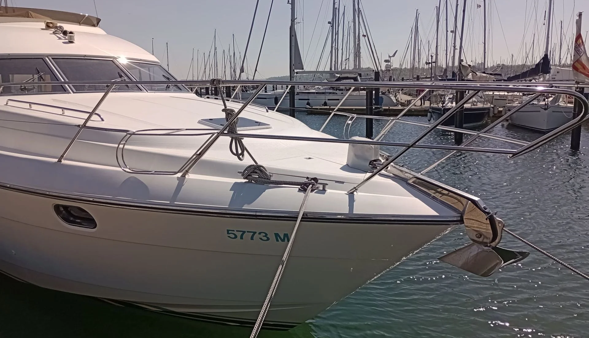 Moored fiberglass motorboat with visible registration number at Jacksonville marina, sailboats in background.