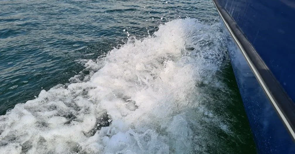 Boat wake churning behind moving vessel in open water, Jacksonville marine conditions.