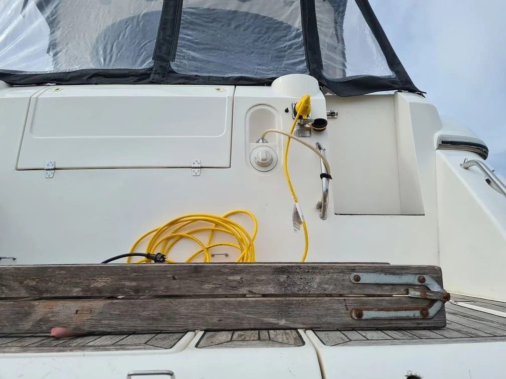 Boat cabin interior showing electrical service setup with yellow power cord and diagnostic equipment mounted on white fiberglass.
