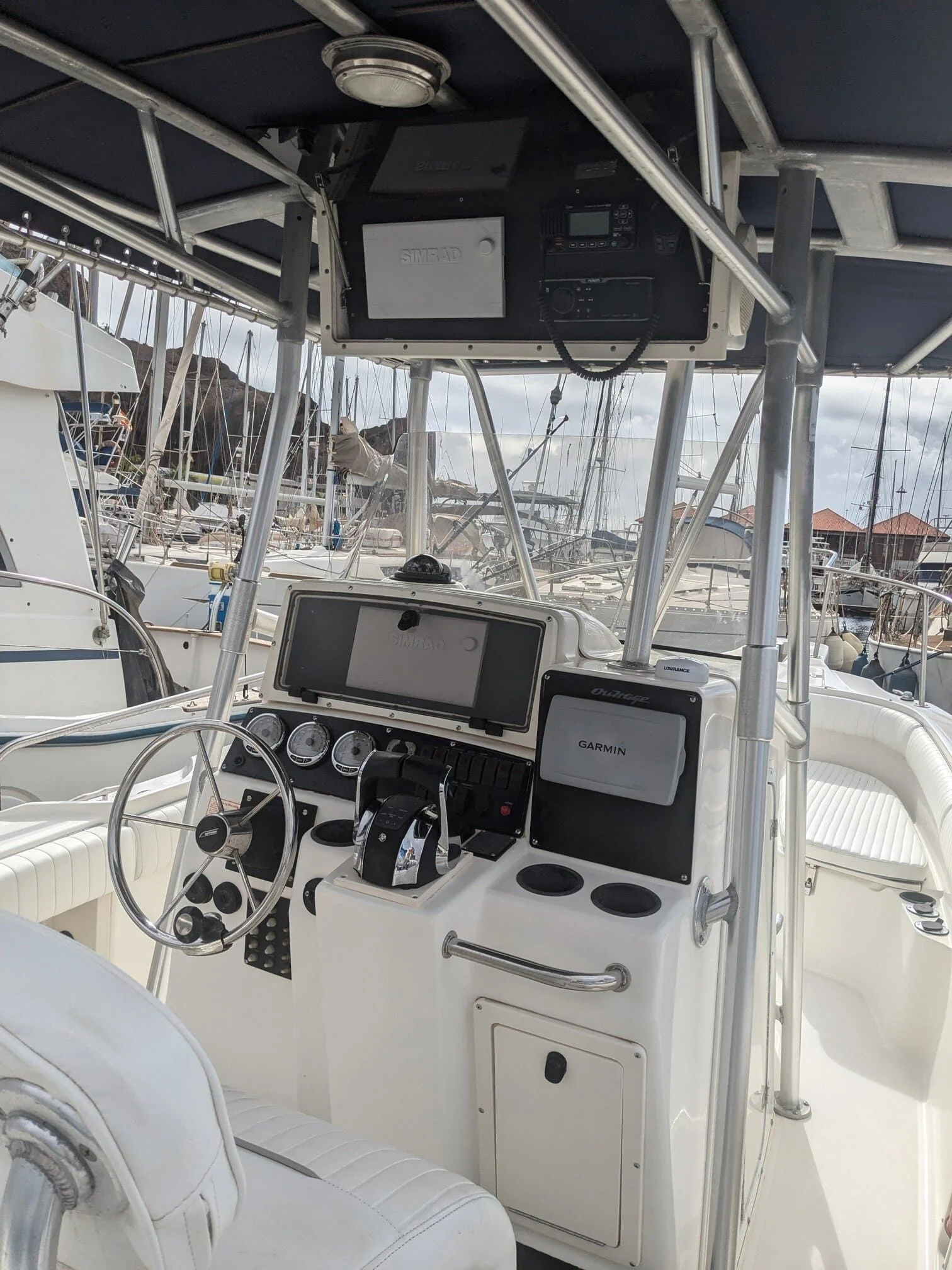 Boat helm console with dual navigation displays and steering wheel dockside.