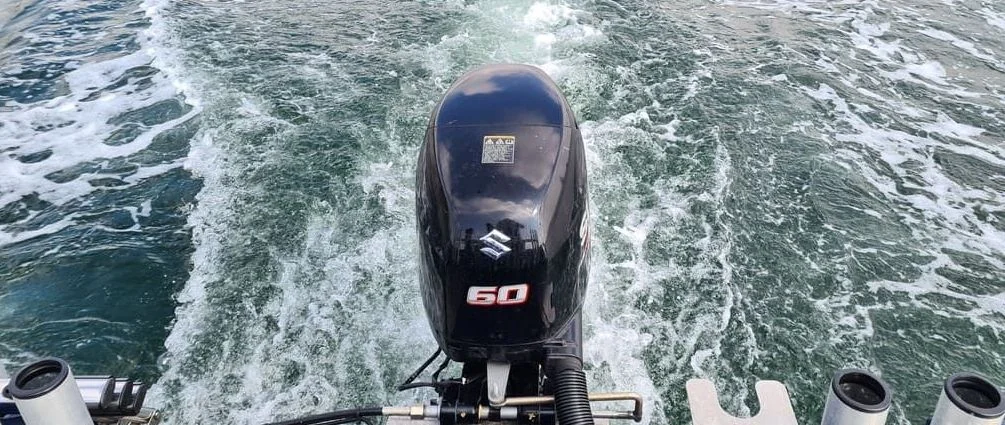 Outboard engine mounted on boat transom during operation in open water.