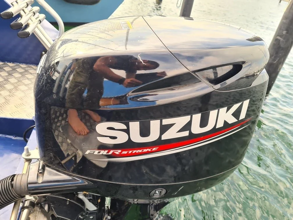 Suzuki outboard engine mounted on boat transom at Jacksonville dockside, showing salt spray weathering.