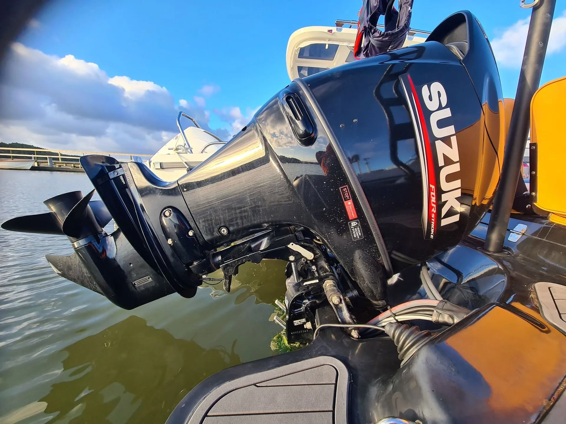 Outboard engine mounted on boat transom dockside, showing mechanical components and water setting.