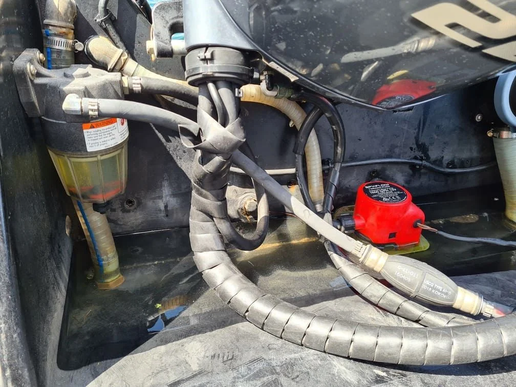 Outboard engine fuel system with filter, hoses, and electrical components during marine diagnostic service.