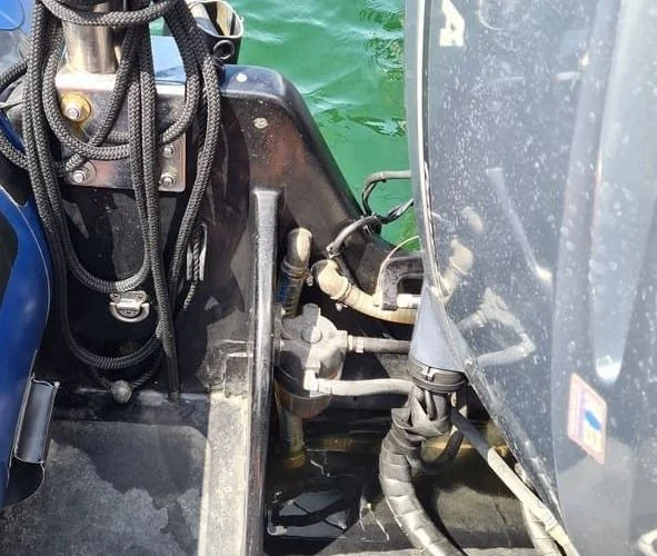 Outboard engine transom bracket and fuel line connections on boat hull in Jacksonville marine service.