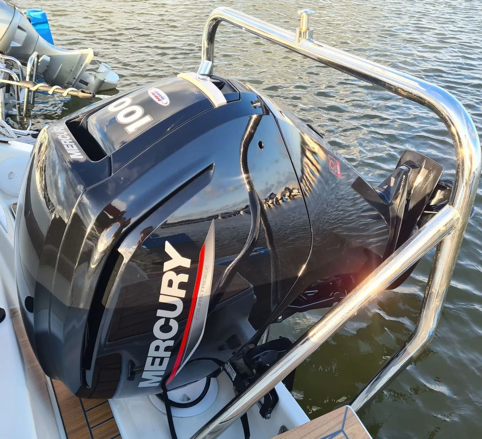 Outboard engine mounted on boat transom at dockside, showing mechanical components and water setting.