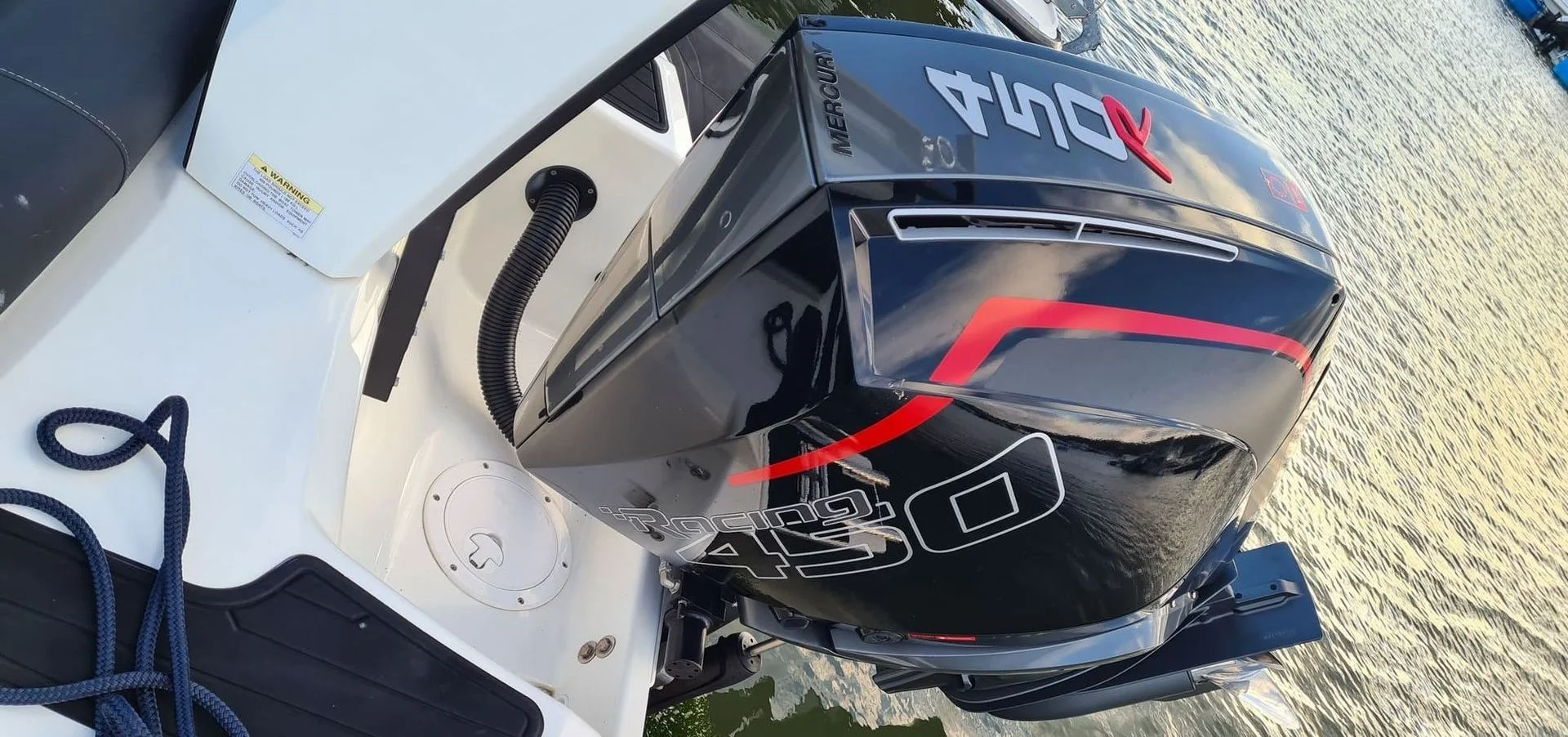 Mercury outboard engine mounted on boat transom, dockside in Jacksonville with water and mooring rope visible.